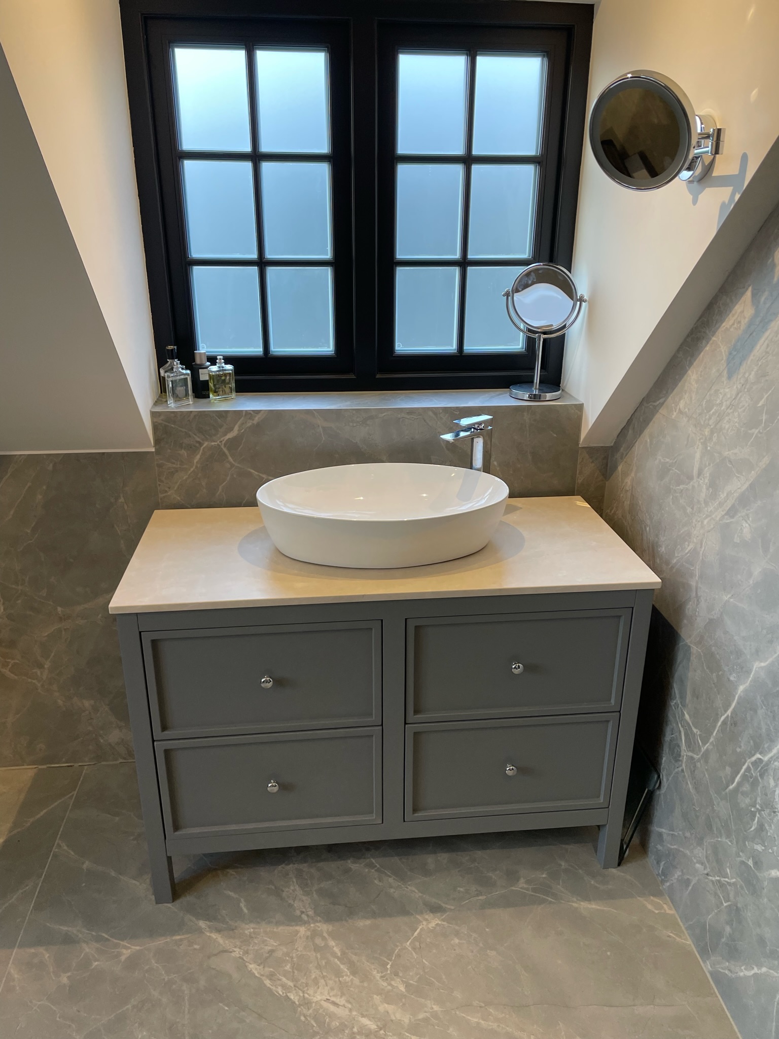 A vessel basin on a bespoke vanity, plumbed in neatly against marble-effect tiling.